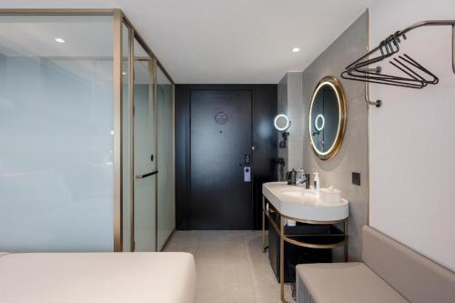 La salle de bains est pourvue d'un lavabo et d'un miroir. dans l'établissement Atour Light Hotel Dalian Xinghai Plaza Xi'an Road, à Dalian