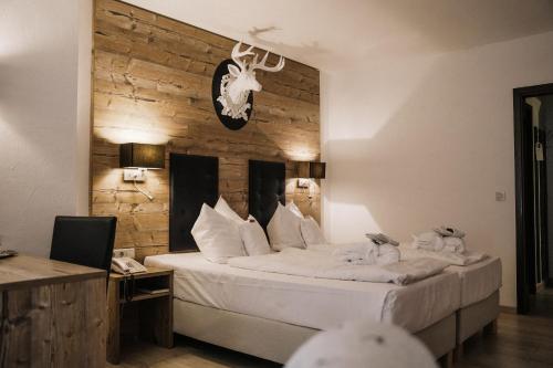 - une chambre avec un grand lit et un mur en bois dans l'établissement Landhotel Waldhaus, à Laubach