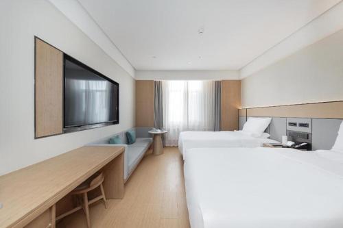 um quarto de hotel com duas camas e uma televisão de ecrã plano em JI Hotel Weihai Liugong Island Tourism Pier em Weihai