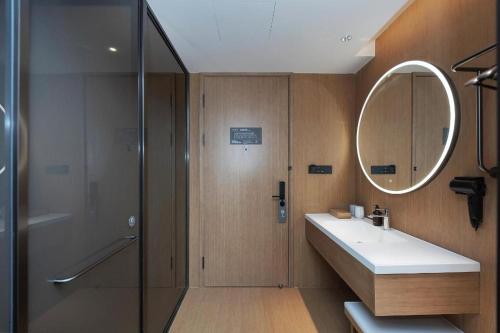 uma casa de banho com um chuveiro, um lavatório e um espelho. em JI Hotel Weihai Liugong Island Tourism Pier em Weihai