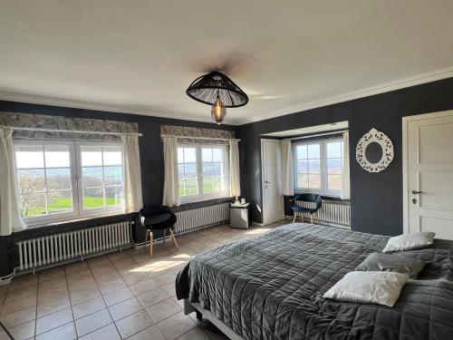 a bedroom with a large bed and windows at Oneux Village in Theux