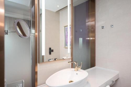 een badkamer met een witte wastafel en een spiegel bij Starway Hotel Nanjing Jiaoyuan Metro Station in Jiexi
