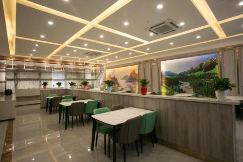 a restaurant with tables and green chairs in a room at Starway Hotel Changji Qitai Bus Station in Xibeiwan