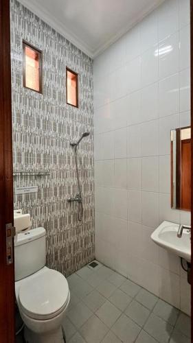 a bathroom with a toilet and a sink at Hens Guesthouse Syariah in Gadobangkong