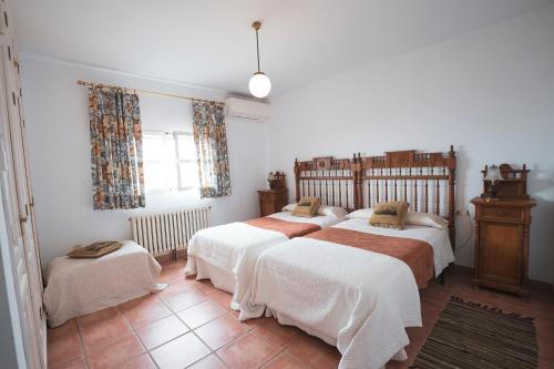 a bedroom with three beds and a window at Casa Rural Dehesa de Solana in Herrera de Alcántara