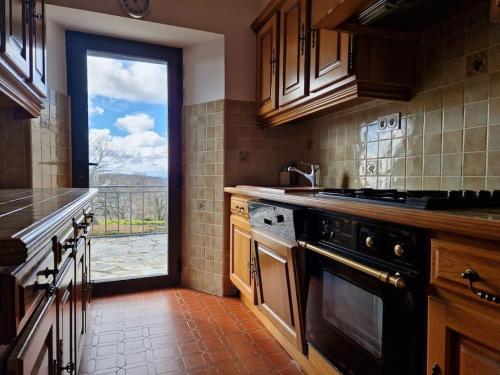 d'une cuisine avec cuisinière et d'une fenêtre avec vue. dans l'établissement La Maison de famille, à Le Nayrac