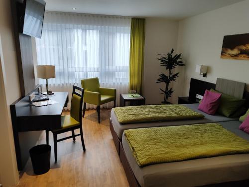 a hotel room with two beds and a desk at Hotel Stock Brotkörble in Friedrichshafen