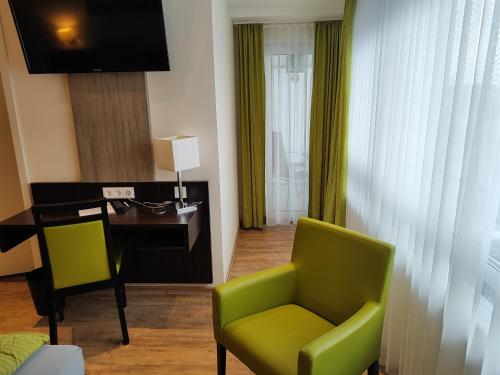 a living room with a desk and a green chair at Hotel Stock Brotkörble in Friedrichshafen