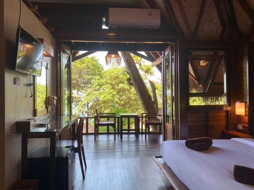 a room with a bed and a balcony with a table at Kohtao Heritage Hideaway in Koh Tao