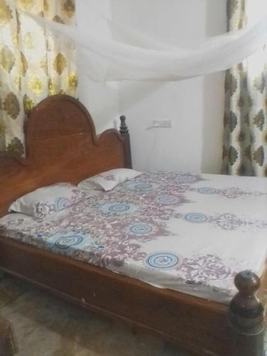 1 dormitorio con 1 cama con cabecero de madera en Mvumoni house, en Kidogo Basi