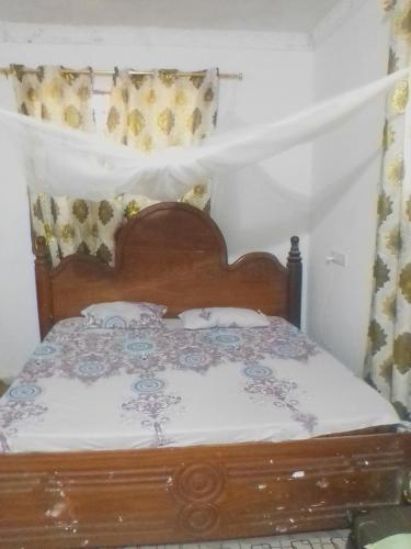 ein Schlafzimmer mit einem Holzbett mit Kissen darauf in der Unterkunft Mvumoni house in Kidogo Basi