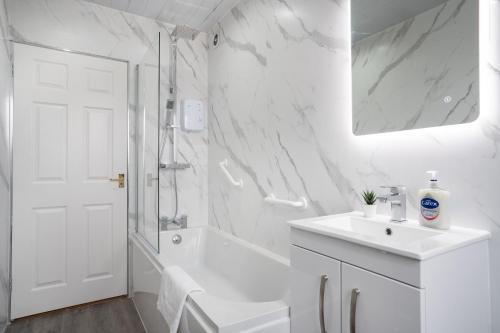 baño blanco con ducha y lavamanos en 2 Bedroom Apartment-Free Parking, en Wishaw