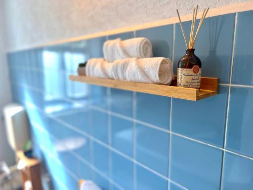 a blue tiled bathroom with a shelf with towels at Bergling Apartment im Zentrum • Netflix • Festungsblick • Obst und Wein • in Königstein an der Elbe