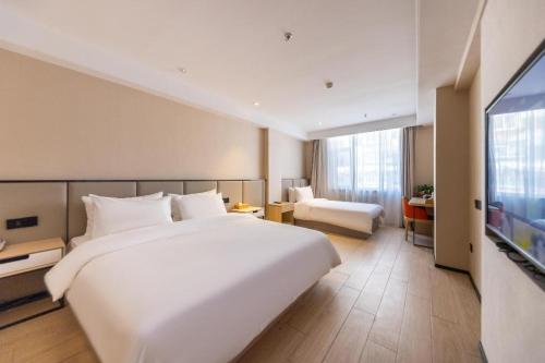 蘭州市にあるStarway Hotel Lanzhou West Passenger Station North Squareの大型ベッド1台、薄型テレビが備わるホテルルームです。