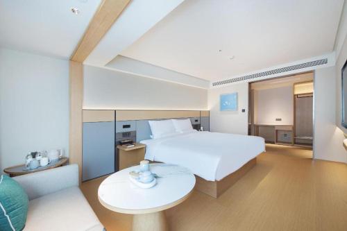 大連的住宿－JI Hotel Dalian Qingniwa Commercial Street，卧室配有一张白色的大床和一张桌子