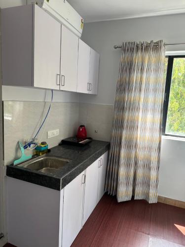 Una cocina con gabinetes blancos y un fregadero y una ventana. en Flow: Private Studio in Koregaon Park. WiFi AC SmartTv, en Pune