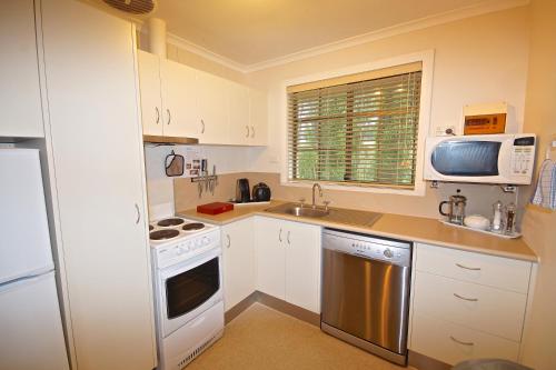a kitchen with white cabinets and a sink and a microwave at Port Arthur Villas in Port Arthur