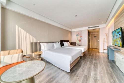 Cette chambre comprend un grand lit et une table. dans l'établissement Hanting Hotel Shaoxing Binhai Commercial Center, à Tangwan