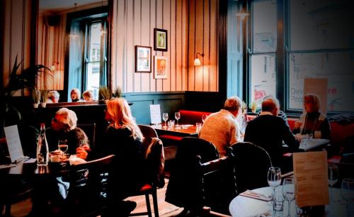 un grupo de personas sentadas en mesas en un restaurante en George Hotel & Granary, en Frome