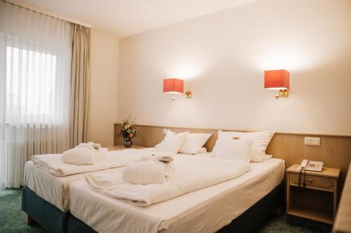 two beds in a hotel room with white pillows at Landhotel Waldhaus in Laubach