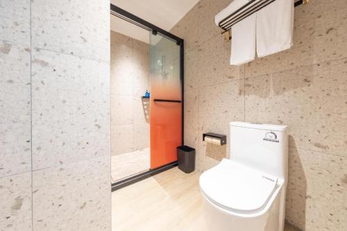 a bathroom with a toilet and a glass door at NIHAO Hotel Linyi Jiefang East Road Financial Building in Linyi