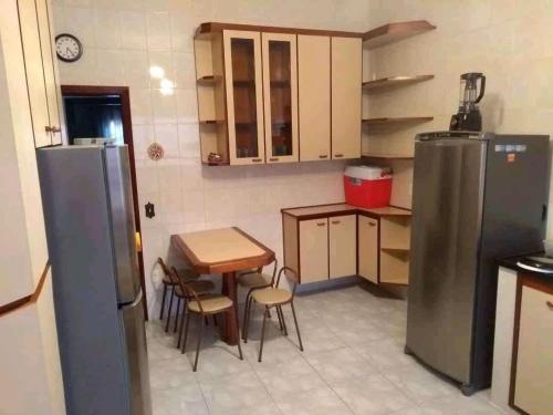 une petite cuisine avec une table et un réfrigérateur dans l'établissement Casa Itanhaém, à Itanhaém