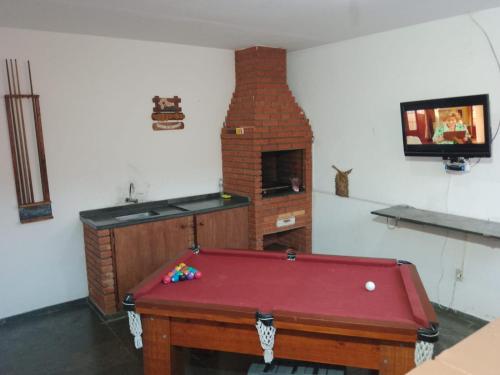 Cette chambre dispose d'un billard et d'une cheminée en briques. dans l'établissement Casa Itanhaém, à Itanhaém