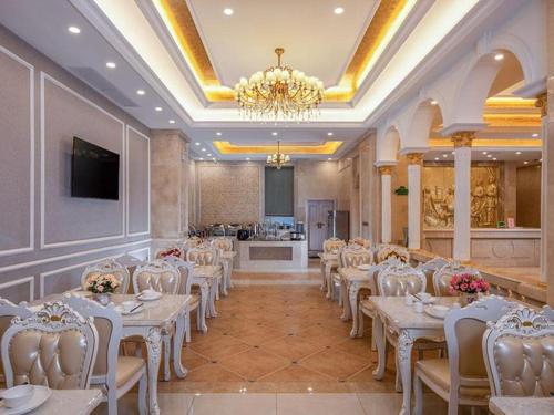 einen Bankettsaal mit weißen Tischen und Stühlen sowie einem Kronleuchter in der Unterkunft Vienna Hotel Yueyang East Station in Yueyang
