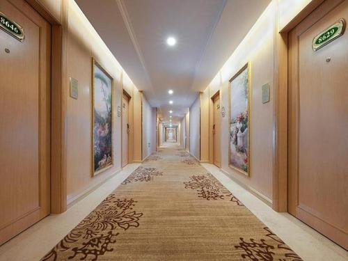 um corredor com um longo corredor com pinturas nas paredes em Vienna Hotel Fuzhou Changle Zhenghe Metro Station em Changle