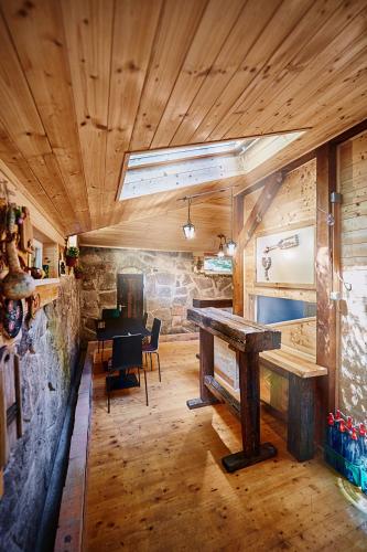 a dining room with a table and a stone wall at Olive Tree Forest Cabin Original in Kismaros