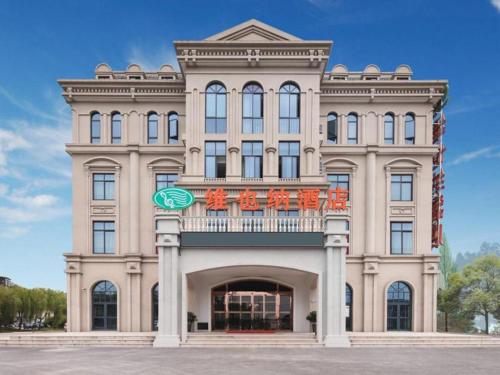 a large building with a balcony on top of it at Vienna Hotel Zhejiang Tongxiang Puyuan in Tongxiang