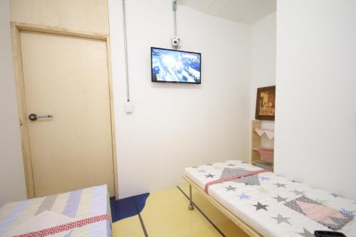 a room with a bed and a door with a picture on the wall at Time Travelers Party Hostel In Hongdae in Seoul