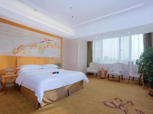 sypialnia z dużym łóżkiem i dużym obrazem na ścianie w obiekcie Vienna Hotel Shandong Laizhou Langhu International Plaza w mieście Laizhou