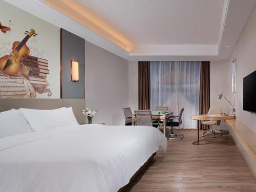um quarto de hotel com uma grande cama branca e uma secretária em Vienna Hotel Guangdong Shaoguan Shaonan Avenue em Shaoguan