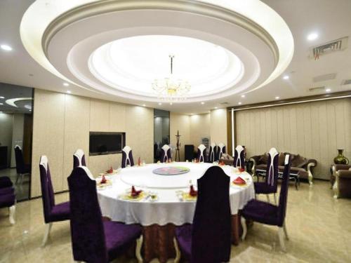uma grande sala de jantar com mesa e cadeiras em Vienna Hotel Shandong Yantai Wanda Plaza Suochengli em Yantai
