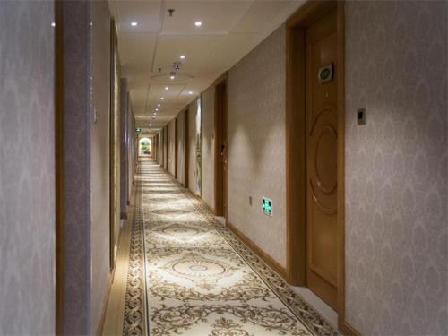 korytarz budynku z podłogą wyłożoną wykładziną i korytarzem w obiekcie Vienna Hotel Inner Mongolia Tongliao Development Zone w Tongliao