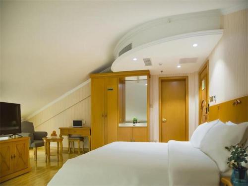 ein Schlafzimmer mit einem großen weißen Bett und einem TV in der Unterkunft Vienna Hotel Inner Mongolia Tongliao Development Zone in Tongliao
