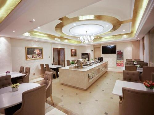 a restaurant with tables and chairs and a chandelier at Vienna Hotel Qinghai Yushu Tangfan Avenue in Chumda