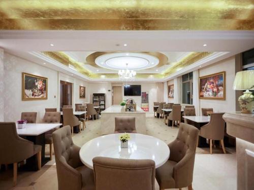 una sala da pranzo con tavoli, sedie e soffitto di Vienna Hotel Qinghai Yushu Tangfan Avenue a Chumda