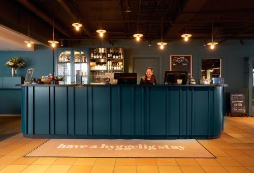 a woman standing at a bar in a room at Clarion Collection Hotel Tollboden in Drammen