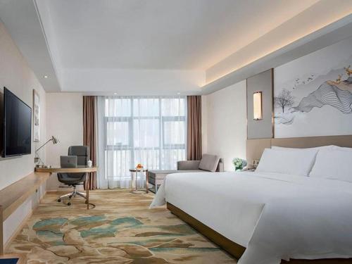 a hotel room with a large bed and a television at Vienna Hotel Shaanxi Hanzhong Central Square High-Speed Railway Station in Hanzhong