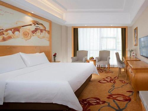 a hotel room with a large white bed and a desk at Vienna Hotel Hunan Chenzhou Municipal Government in Chenzhou