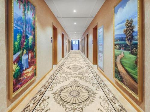 un corridoio con dipinti sulle pareti di un edificio di Vienna Hotel Taicang Zhenghe Road a Zhoujiating