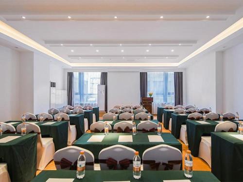 una stanza con tavoli e sedie verdi con bottiglie sopra di Vienna Hotel Taicang Zhenghe Road a Zhoujiating