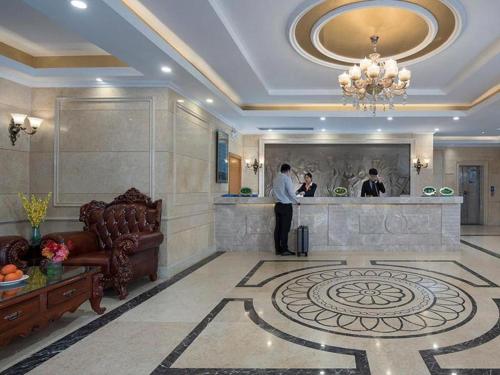 a lobby with two people standing at a counter at Vienna Hotel Anhui Bozhou Lixin Yuanli Plaza in Lixin
