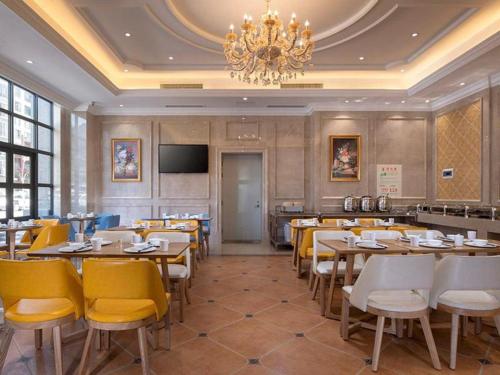 um restaurante com mesas e cadeiras e um lustre em Vienna Hotel Yunnan Dali Erhai Lake em Dali