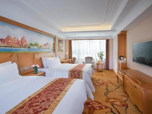 a hotel room with two beds and a flat screen tv at Vienna Hotel Ganzhou Economic Development Zone 1st Hospital West High-Speed Railway Station in Ganzhou