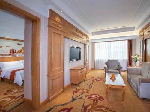 a hotel room with a bed and a living room at Vienna Hotel Ganzhou Economic Development Zone 1st Hospital West High-Speed Railway Station in Ganzhou