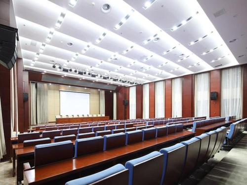 una sala de conferencias con filas de sillas y una pantalla en Venus Royal Hotel Ordos Yijinhuoluo Banner Olympic en Ordos