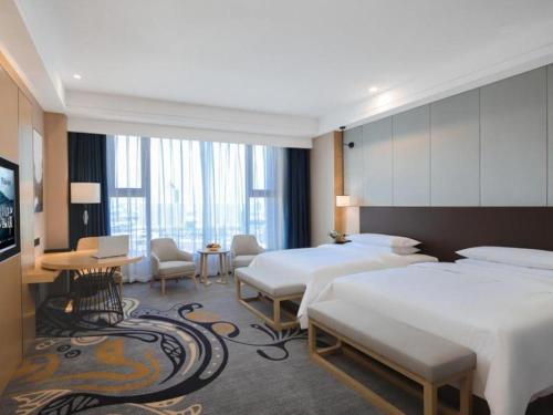 um quarto de hotel com duas camas e uma televisão em Venus Royal Hotel Ordos Yijinhuoluo Banner Olympic em Ordos